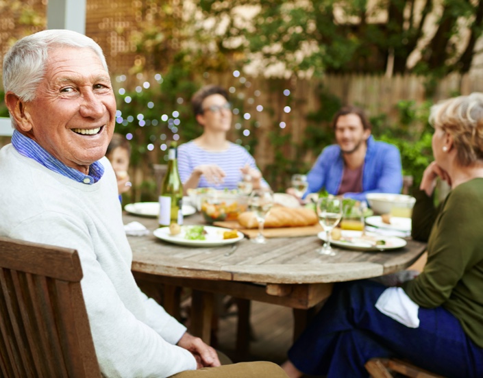 Group of people sitting outside while eating dinner and smiling